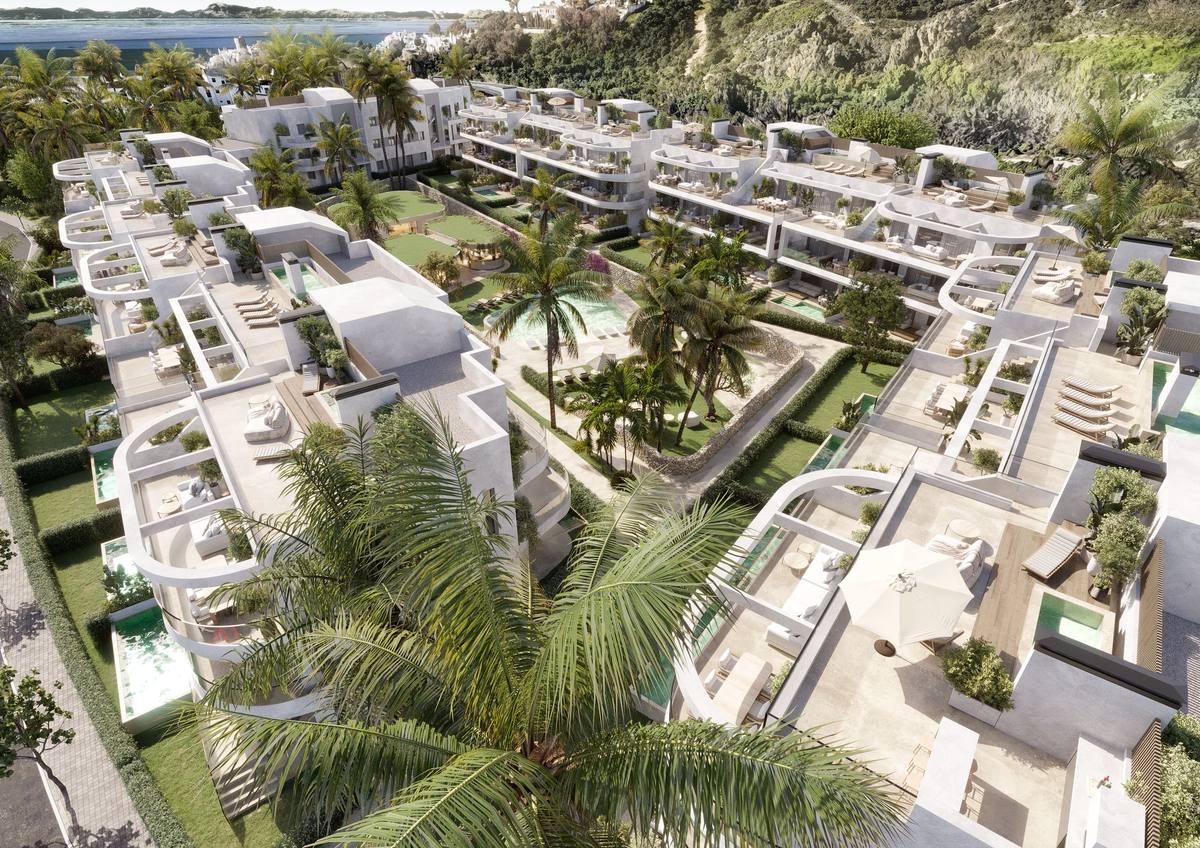 Luchtfoto van The Palms at Estepona: witte appartementengebouwen met dakterrassen rond een tuin met palmen en zwembad